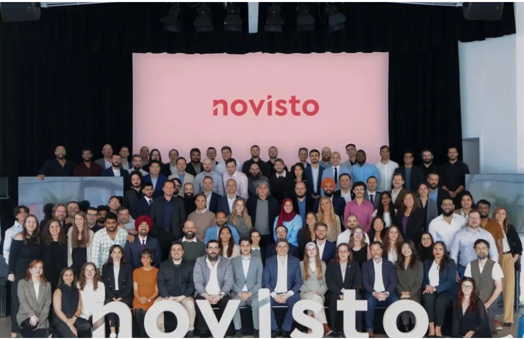 Group photo of Novisto employees at company headquarters in Montreal, standing together in front of a screen with the Novisto logo.