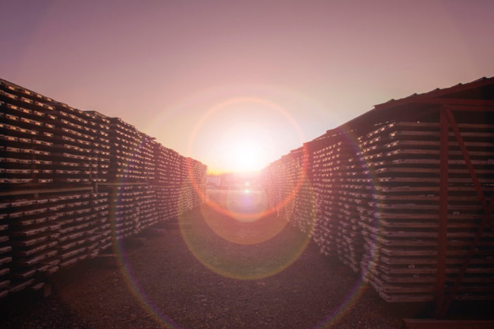 Rows of stacked industrial materials at an outdoor site at sunset.